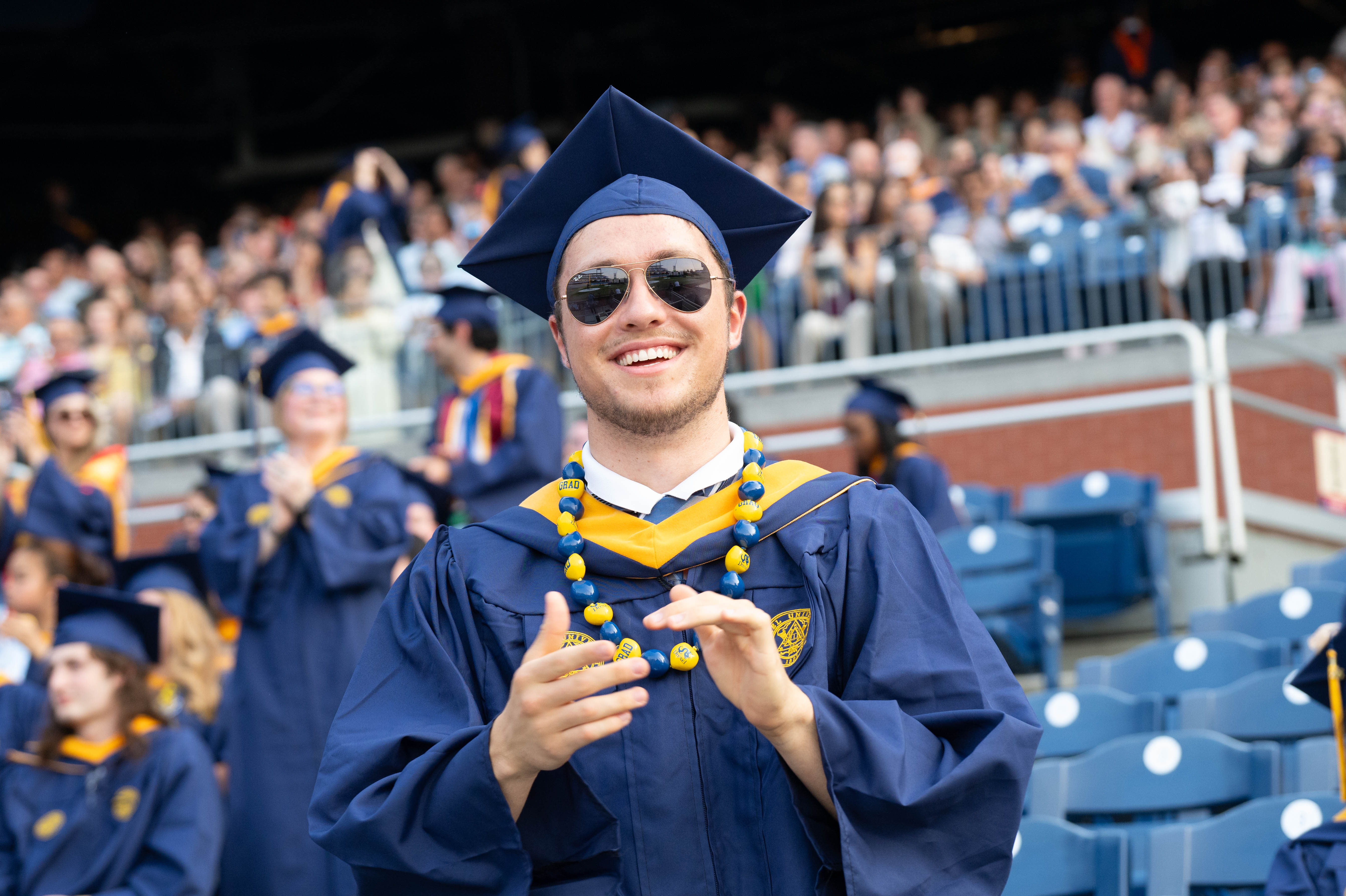 A student clapping with a Drexel necklace.