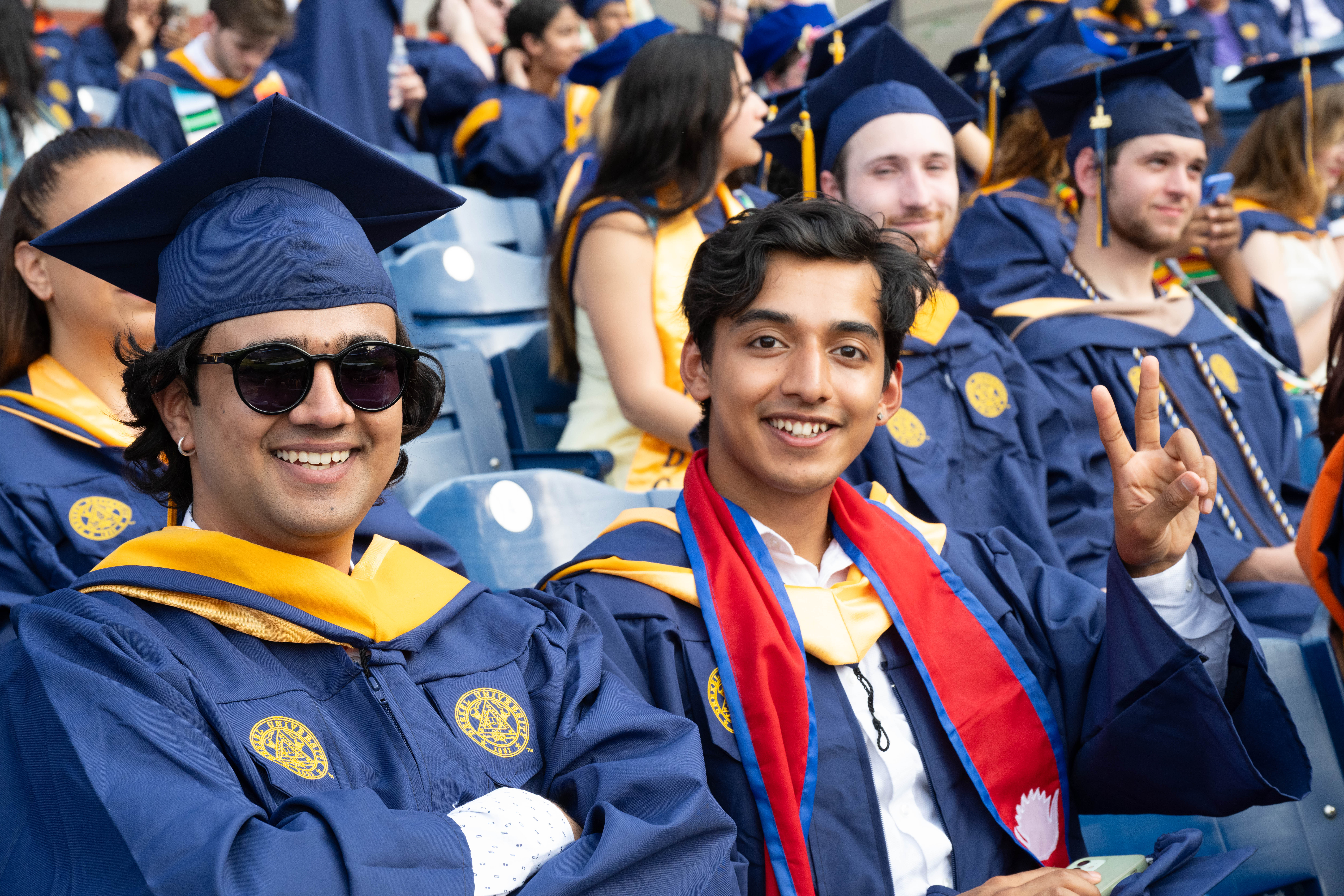 A male student giving a peace sign next to another student.