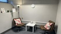Two leather chairs with colorful pillows stationed around a table in a room with minimal decorations.
