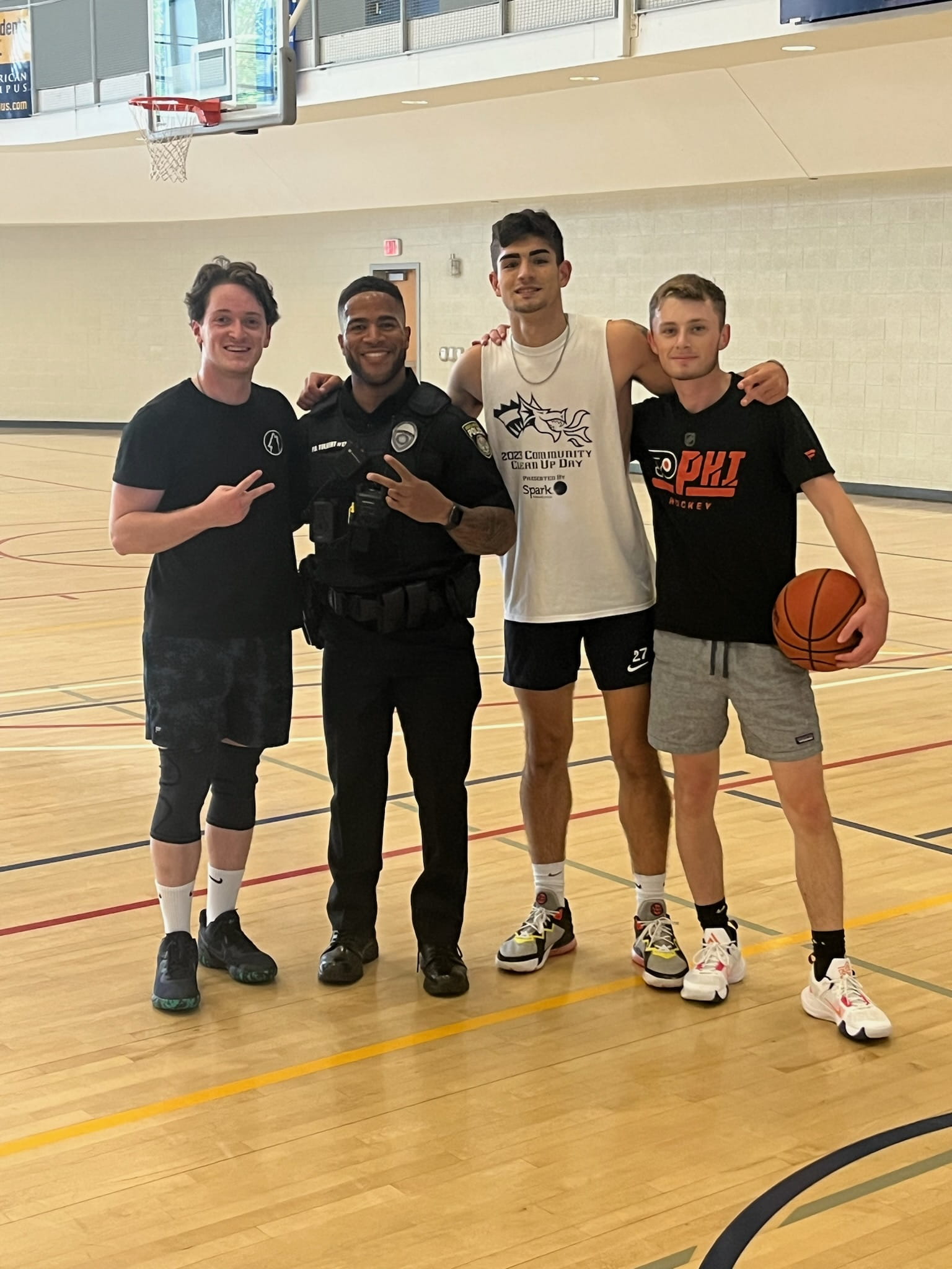 Four young adolescent boys stand next to each other on a basketball court.