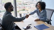man and woman shaking hands across a desk