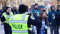 Image of two people wearing fluorescent police vests on Drexel&#39;s campus directing foot traffic of people wearing Eagles jerseys and apparel.
