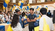 Graduate students at orientation in Main Building with blue and gold balloons