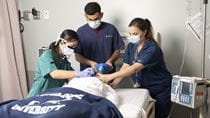 3 nursing students tend to a dummy patient in a simulation lab