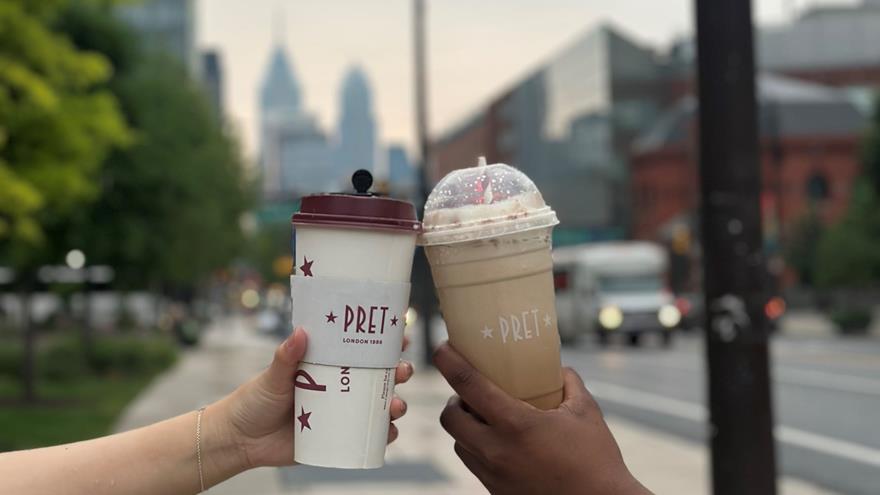 Hot and cold lattes held up in front of Market Street