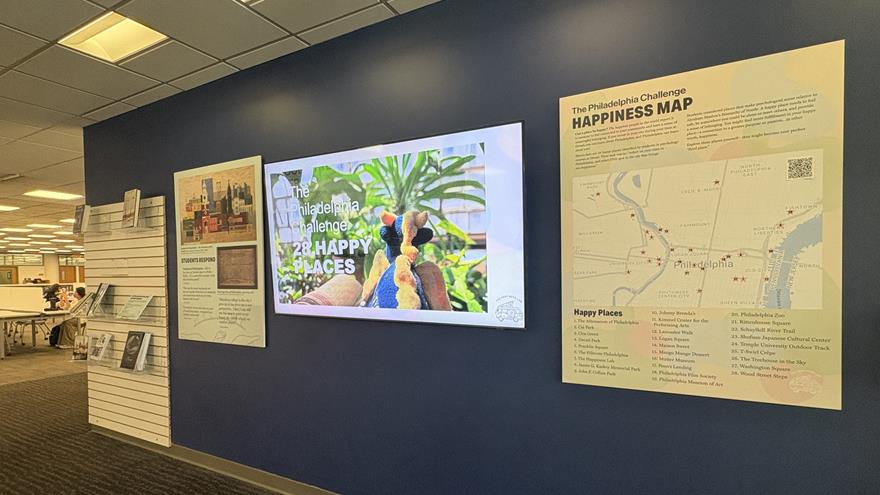 Wall containing posters and a TV screen with &quot;The Philadelphia Challenge&quot;