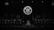 People on a stage at graduation with a podium and Drexel seal