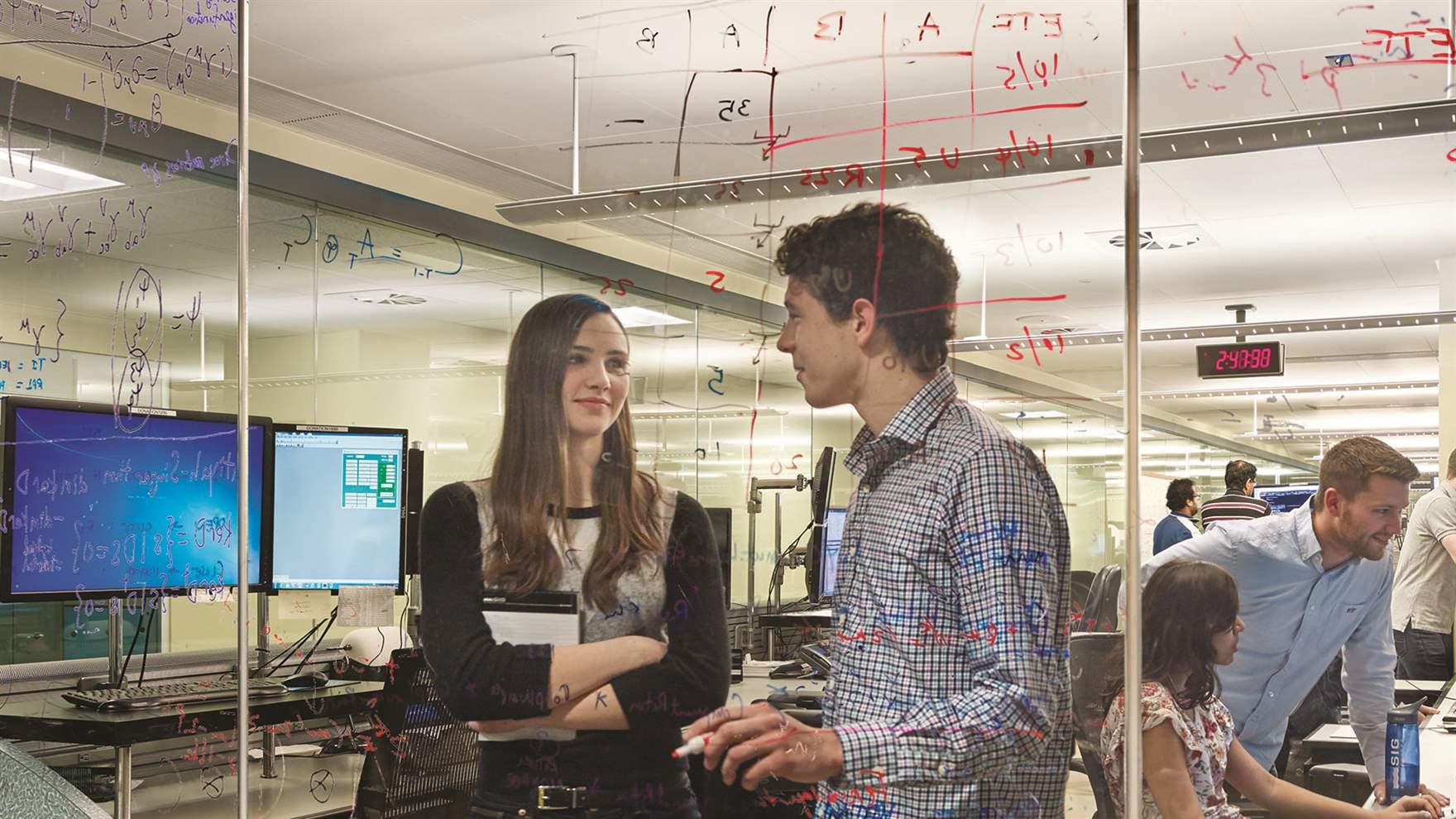 Two students converse in a computer lab